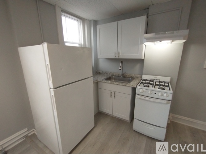 A small kitchen with a white fridge, stove, and cabinets.