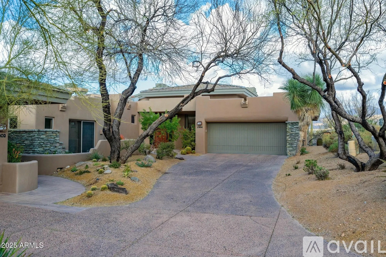 A house with a driveway and trees in front of it.