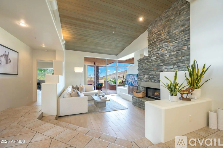 A modern living room with a stone fireplace and a large painting on the wall.