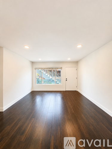 A room with wooden floors and a window overlooking a balcony.