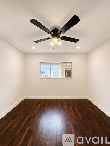 A room with a ceiling fan and wooden flooring.