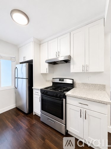 A kitchen with white cabinets and a stainless steel refrigerator.