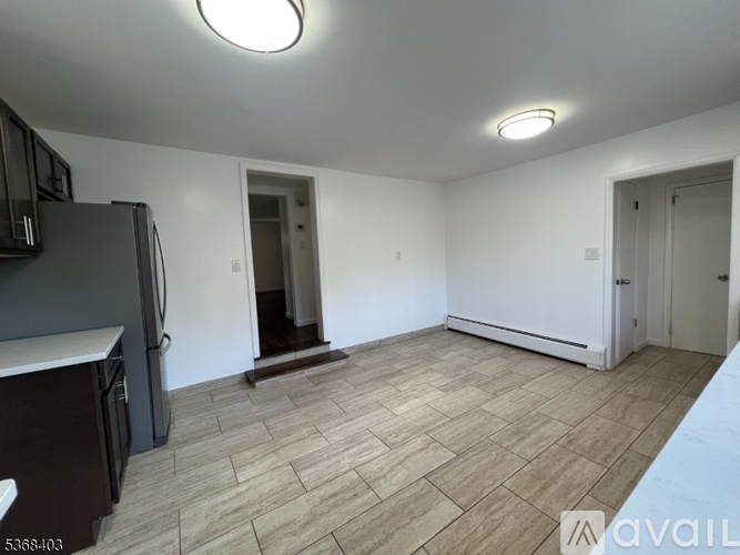 A kitchen with a black fridge and wooden flooring.