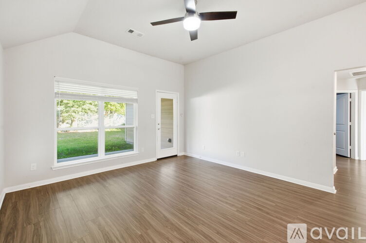 A spacious room with a ceiling fan and wooden flooring.