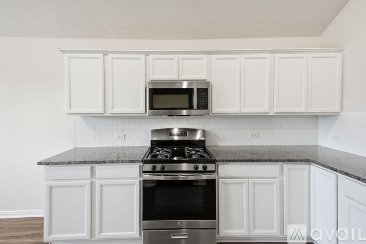 A kitchen with white cabinets and a granite countertop.