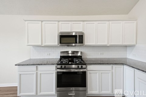 A kitchen with white cabinets and a granite countertop.
