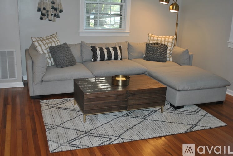 A grey couch with a wooden coffee table in front of it.