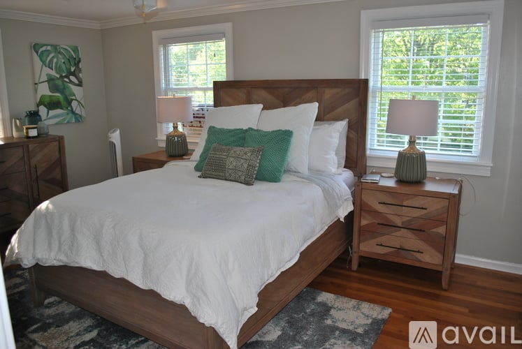 A bedroom with a large bed, a nightstand, and a window with blinds.