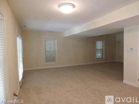 A spacious room with a window and a door on the right side.