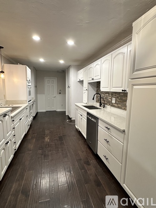 A kitchen with white cabinets and a black floor.