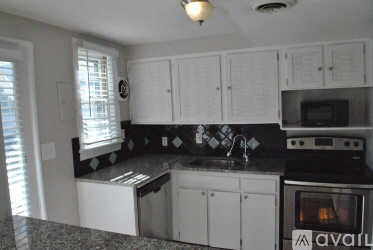 A kitchen with white cabinets and a black and white checkered backsplash.