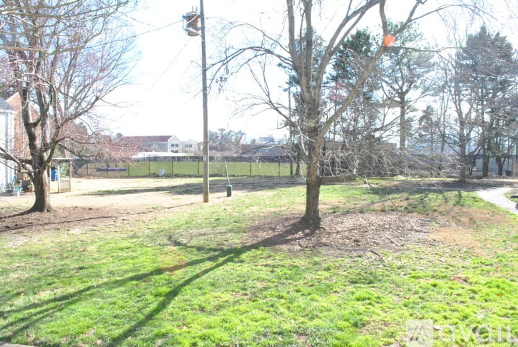 A grassy area with trees and a pole in the distance.