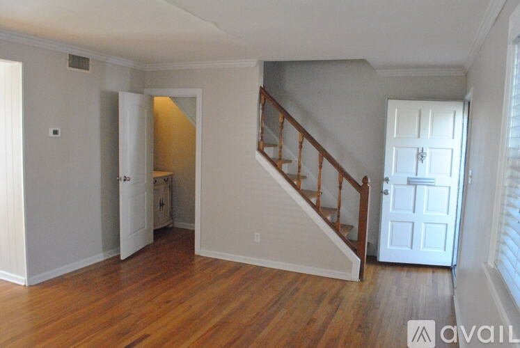 A room with wooden floors and a staircase leading to another room.