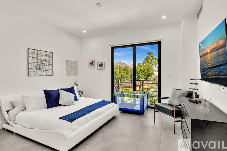 A bedroom with a large bed and a view of the outdoors through a sliding glass door.