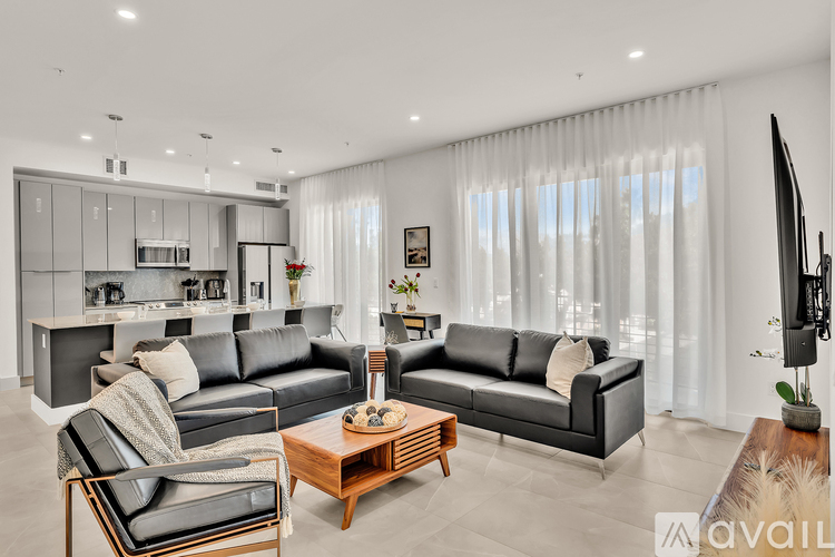 A modern living room with black leather sofas and a wooden coffee table.