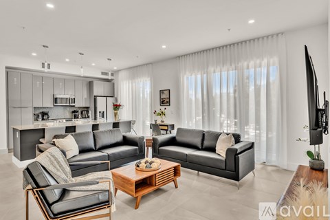 A modern living room with black leather sofas and a wooden coffee table.