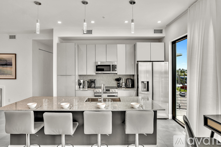 A modern kitchen with white chairs and a large island.