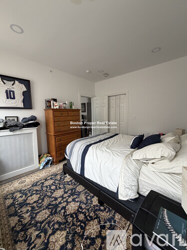 A bedroom with a large bed and a jersey on the wall.