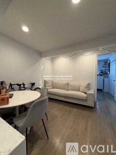 A living room with a white couch and a table with a bottle on it.
