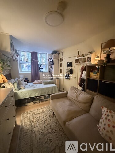 A bedroom with a bed, couch, and a rug.