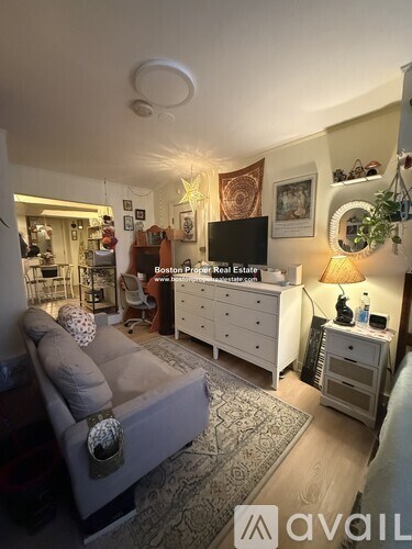 A living room with a grey couch and a white dresser.