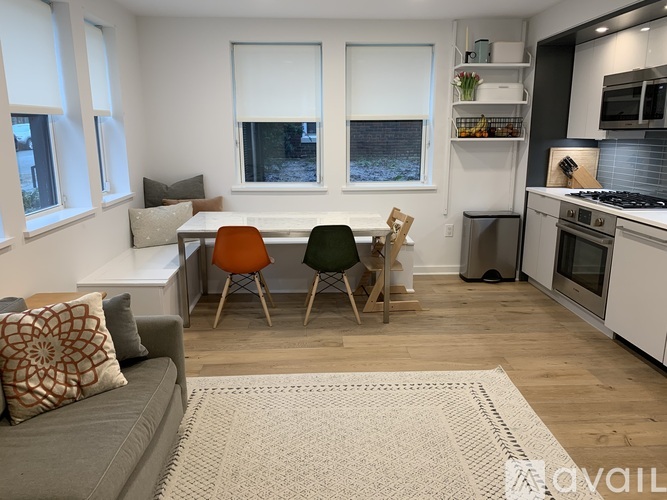 A kitchen with a grey couch and a white table with a brown chair.