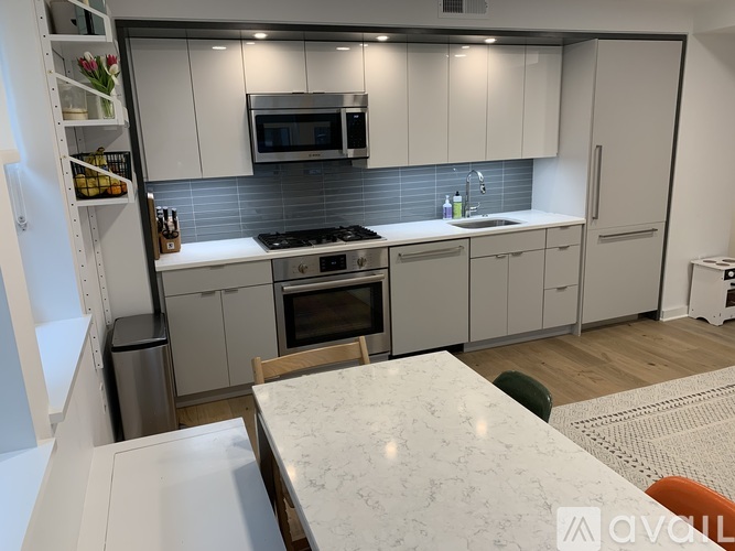 A modern kitchen with white cabinets and a marble countertop.