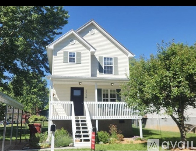 A two-story house with a porch and a black door.
