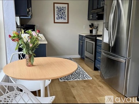 A kitchen with a round table and a vase of flowers on it.