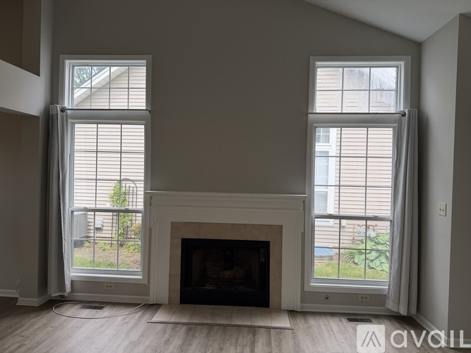 A living room with a fireplace and two windows.