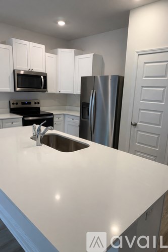 A kitchen with white cabinets and a stainless steel refrigerator.
