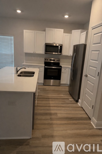 A kitchen with white cabinets and a wooden floor.