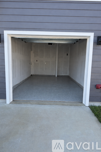 A garage door is open, revealing a clean, empty garage inside.