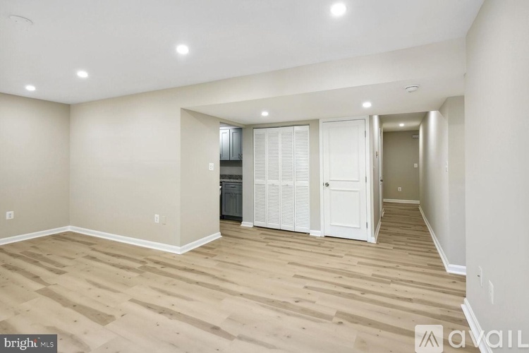 A spacious room with wooden flooring and white walls.
