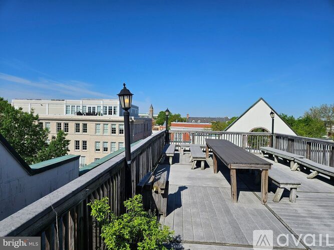 A wooden deck with benches and a lamp post is in the foreground with a building in the background.