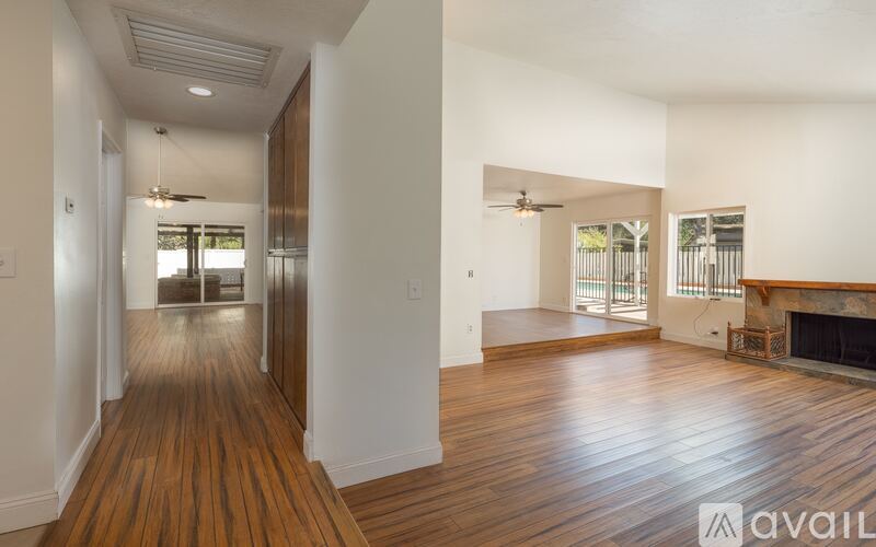 A spacious room with wooden floors and a fireplace.