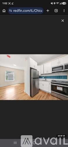 A kitchen with white cabinets and a black refrigerator.