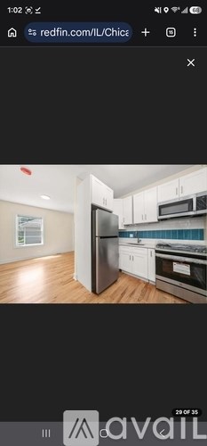 A kitchen with white cabinets and a black refrigerator.