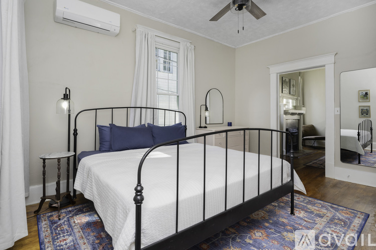 A bedroom with a black metal bed frame and a white bedspread.
