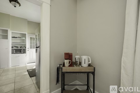 A kitchen area with a table holding a coffee maker and a white mug.