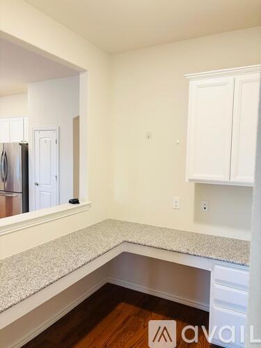 A kitchen with white cabinets and a granite countertop.