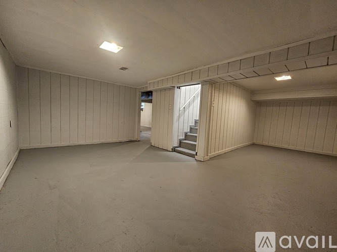 A spacious room with a staircase leading to another room.