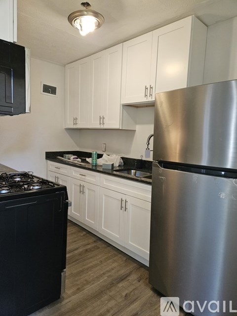 A kitchen with white cabinets and a stainless steel refrigerator.