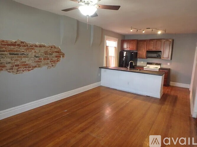 A kitchen with wooden floors and a brick wall.