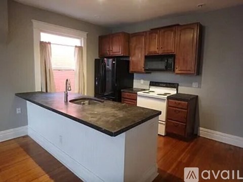 A kitchen with wooden cabinets and a black refrigerator.