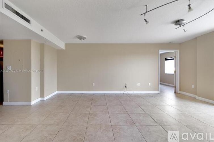 A spacious empty room with tiled flooring and white walls.