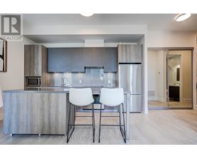A modern kitchen with a bar area and two white chairs.