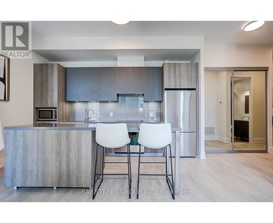 A modern kitchen with a bar area and two white chairs.