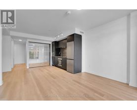 A spacious room with wooden flooring and a large, dark-colored cabinet with a glass door.