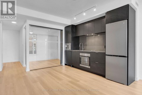 A modern kitchen with dark cabinets and a wooden floor.